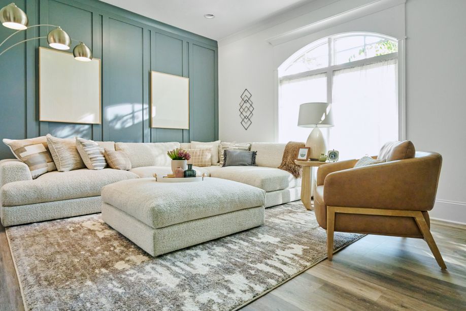 Living room with a sectional sofa, ottoman, and accent chair.
