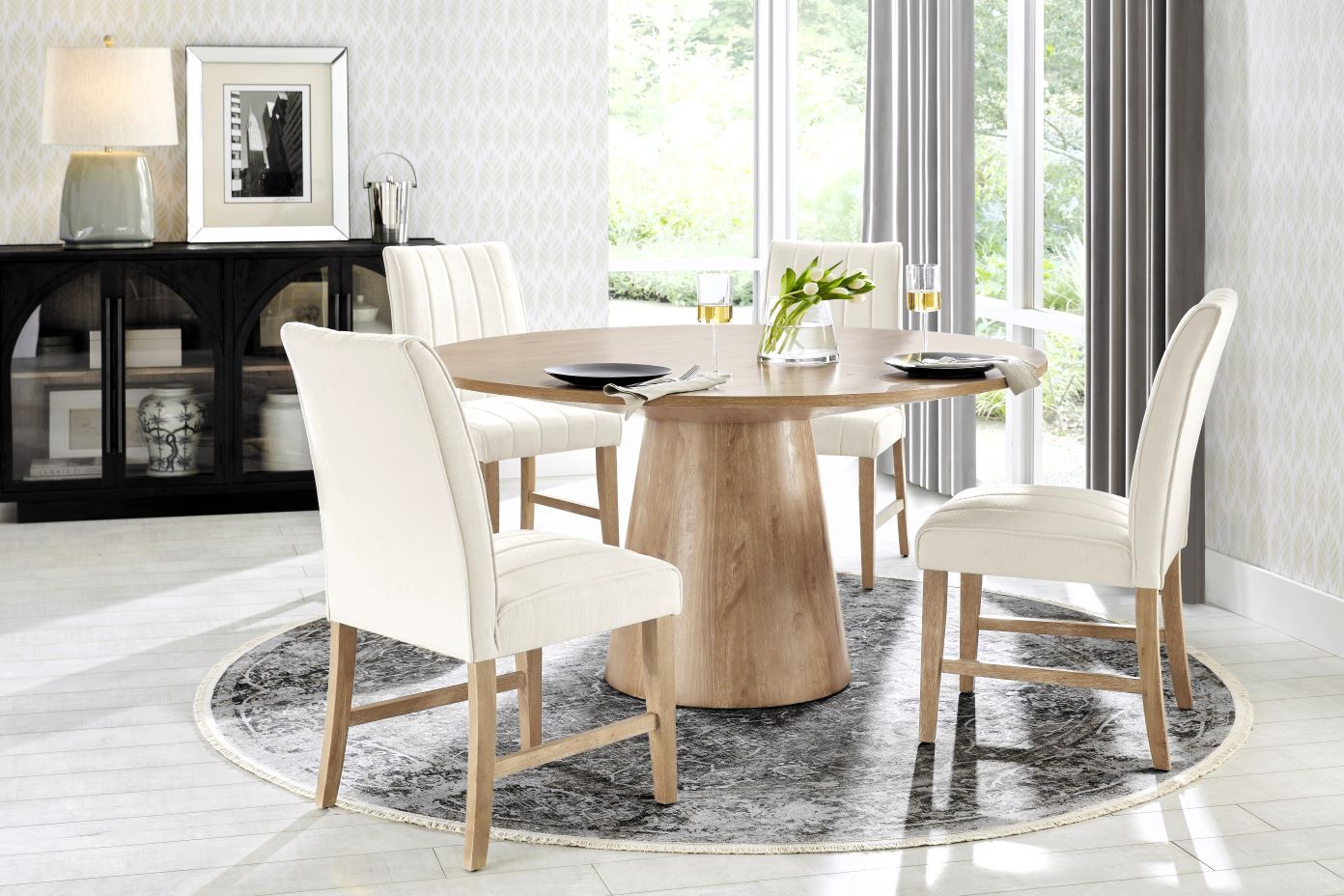 Dining room with a round wooden table, four white chairs, and a patterned rug.
