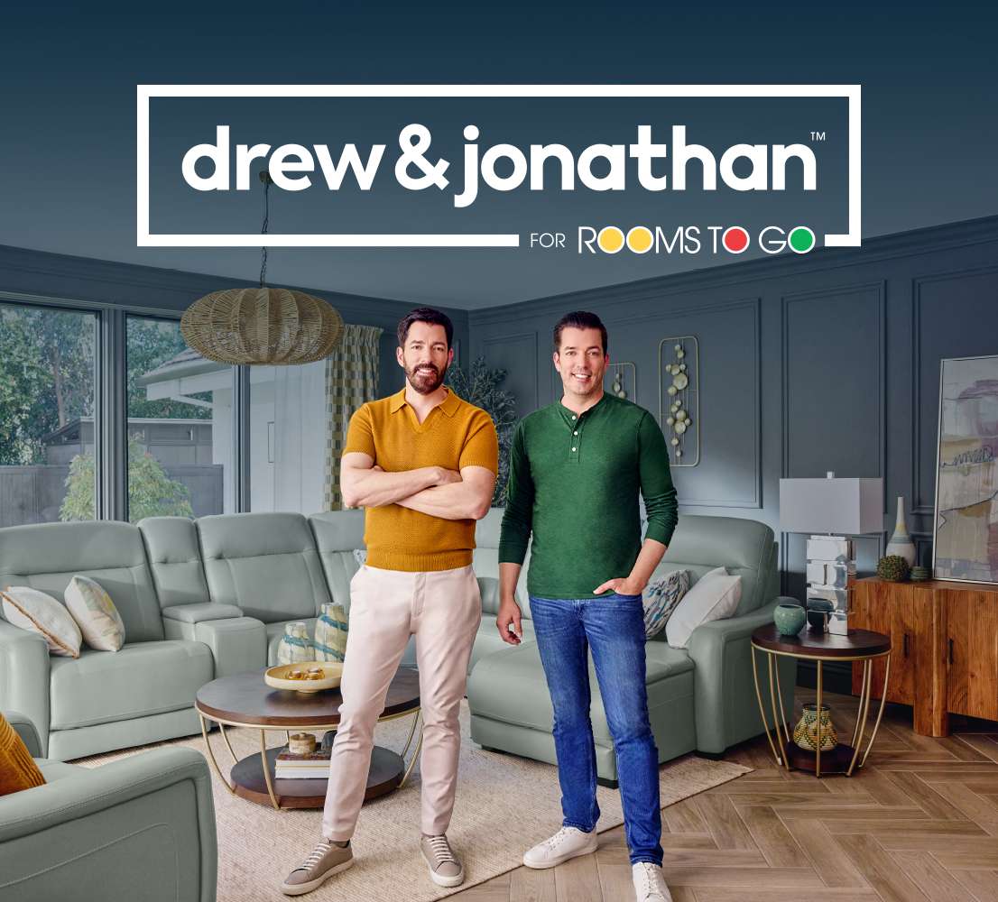 drew & jonathan for Rooms To Go. Two men stand in a living room with furniture.
