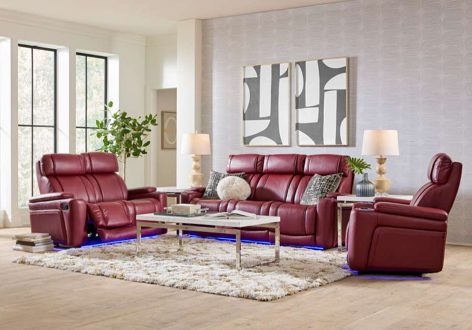 A living room with red leather reclining furniture, a white coffee table, and a fluffy rug.

