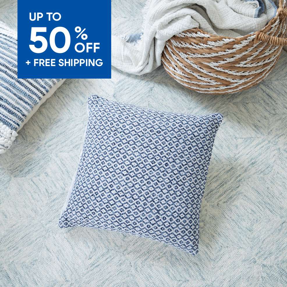 Up to 50% off + free shipping. A blue and white patterned pillow on a light blue rug.