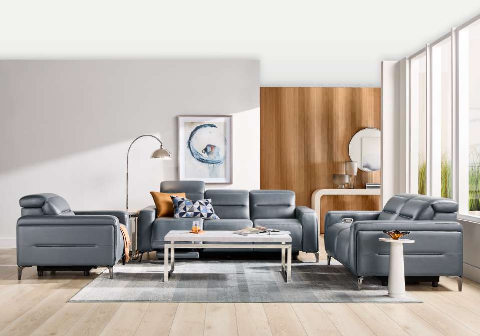 A modern living room with gray leather furniture, a coffee table, and a rug.

