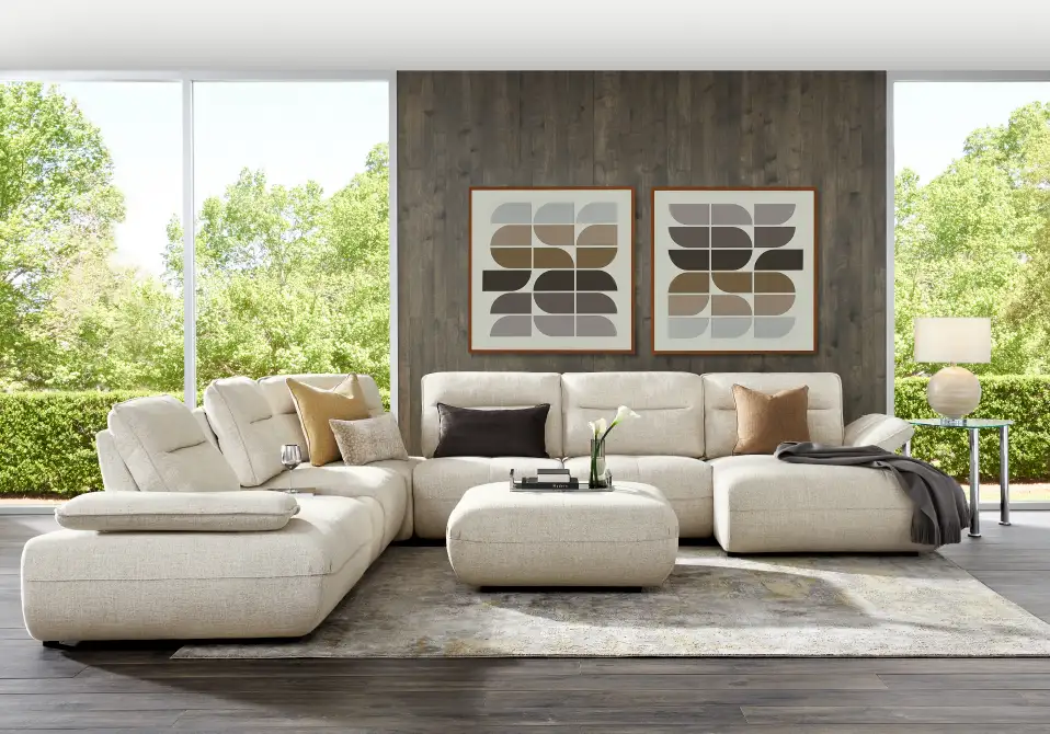 A sectional sofa with an ottoman, rug, and artwork.
