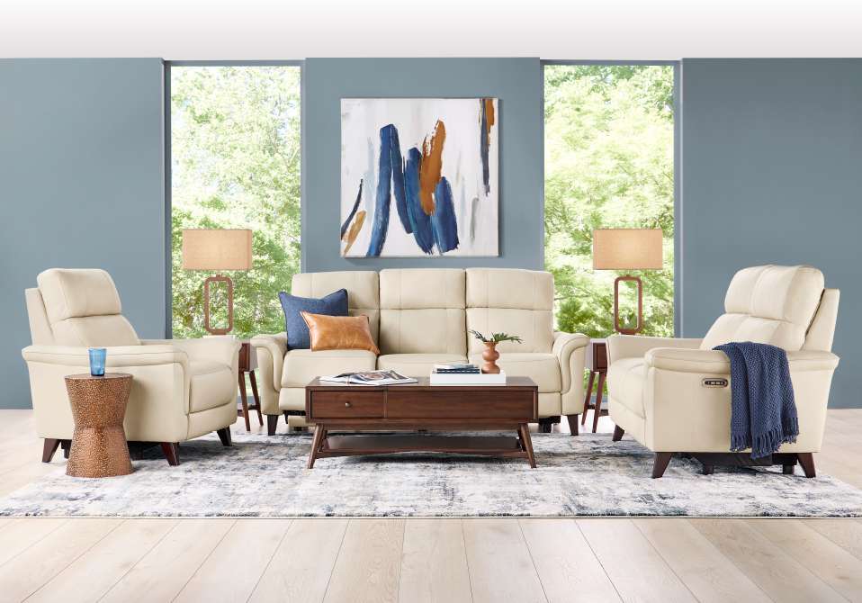 Living room with cream-colored furniture, a blue rug, and abstract art.