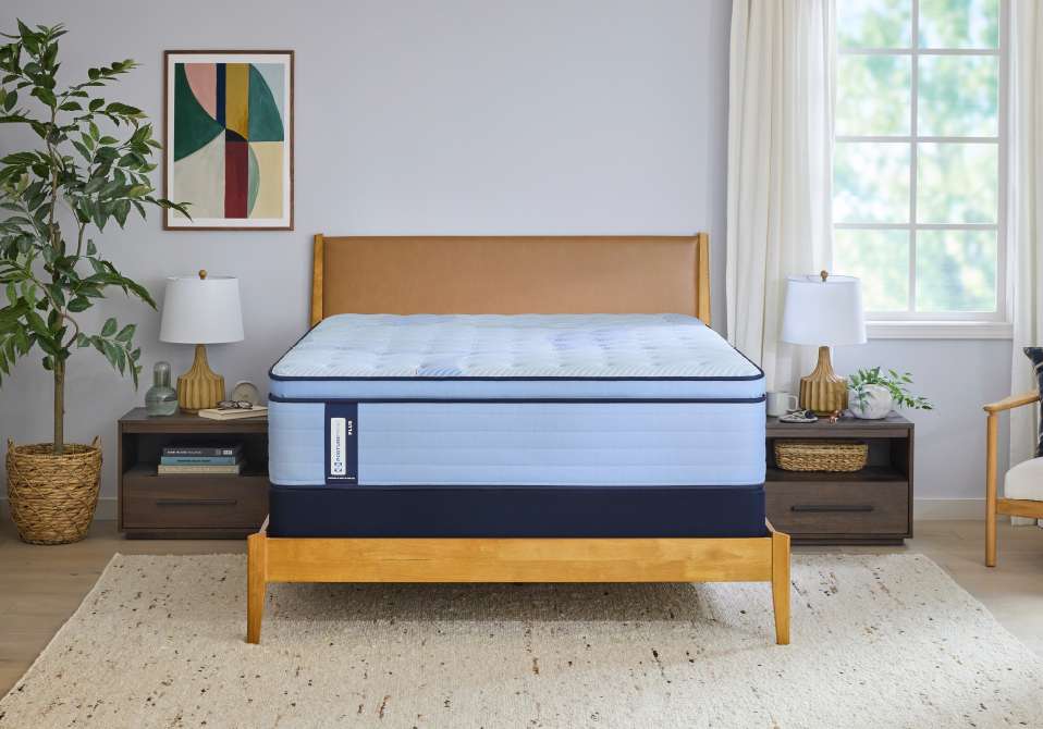 A bed with a light blue mattress and a brown headboard.
