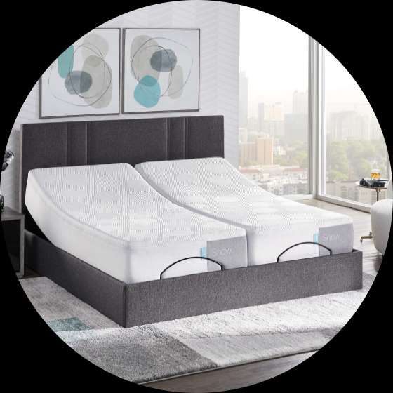 A split adjustable bed with a gray headboard and a city view.
