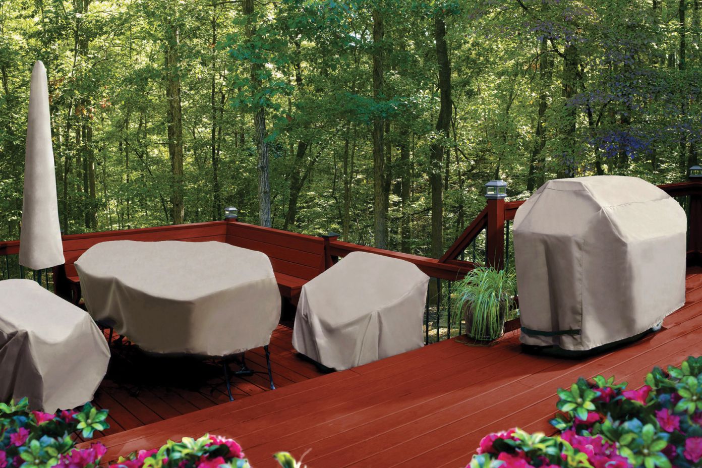 Outdoor furniture covered with tan protective covers on a wooden deck.
