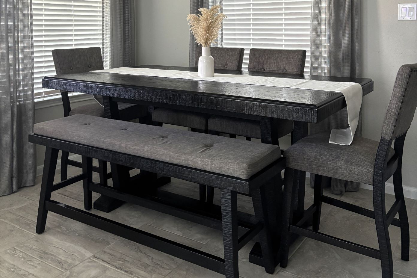 Black dining table with a bench and chairs.
