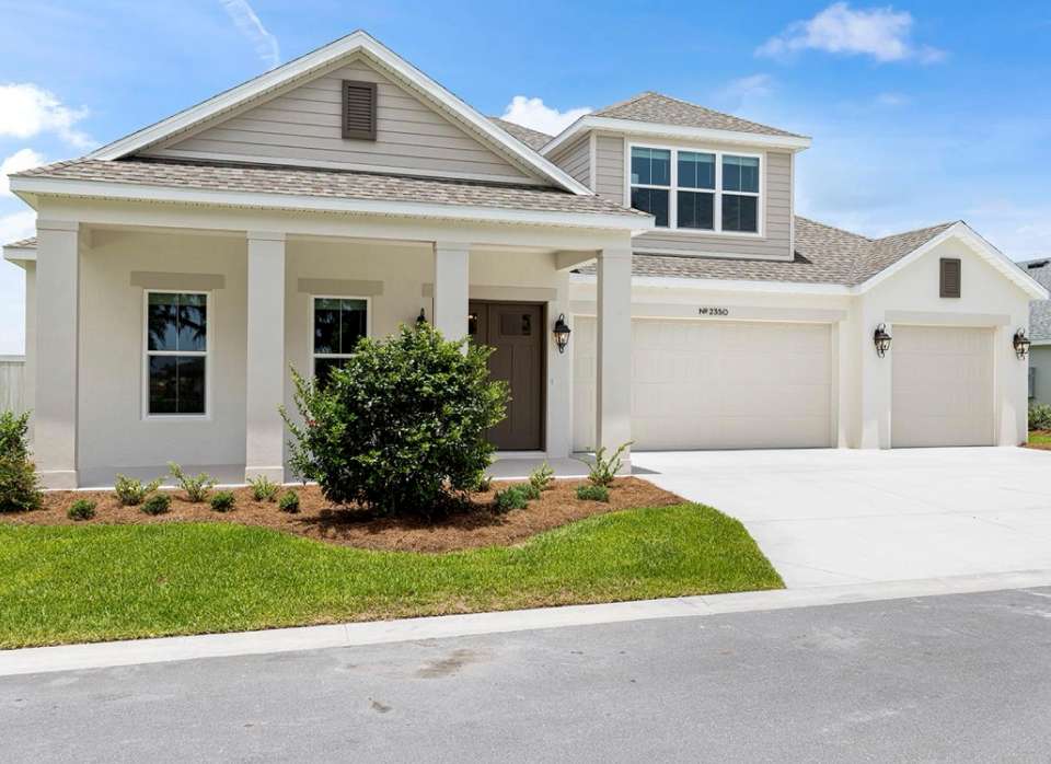 A modern house with a light-colored exterior, a brown door, and a two-car garage.
