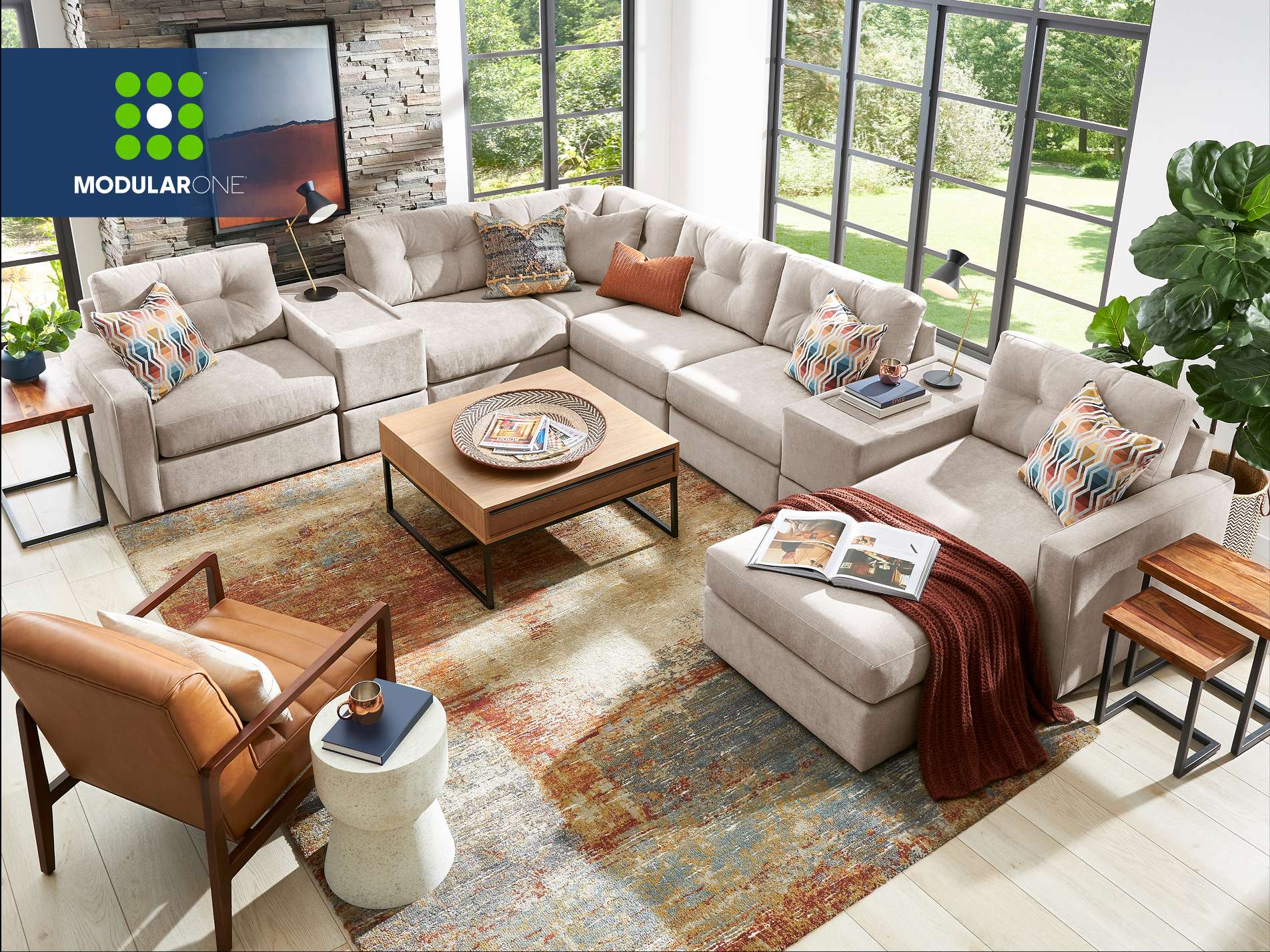 Modular One. A modern sectional sofa with colorful pillows, a coffee table, and a rug.
