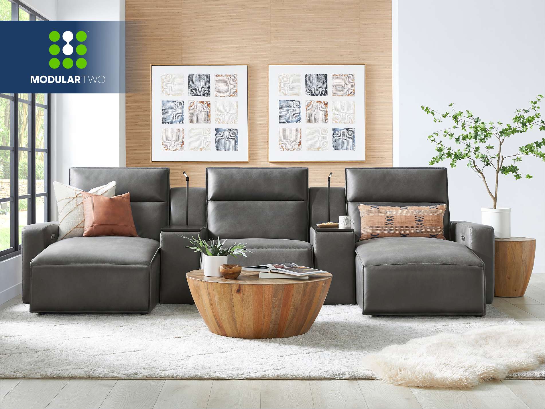 ModularTwo. A modern gray leather sectional sofa with a wooden coffee table and artwork.
