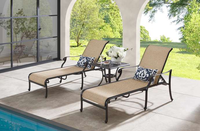 Two chaise lounges with pillows and a small table on a patio.
