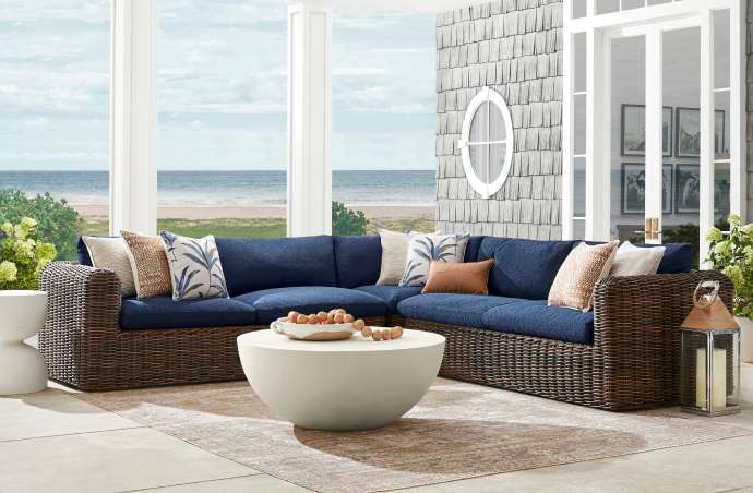Outdoor sectional sofa with blue cushions and woven brown frame.