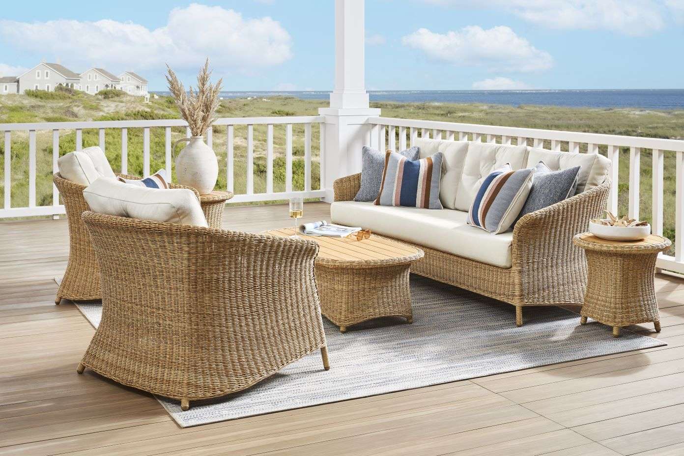 Outdoor wicker furniture set on a deck overlooking the ocean.
