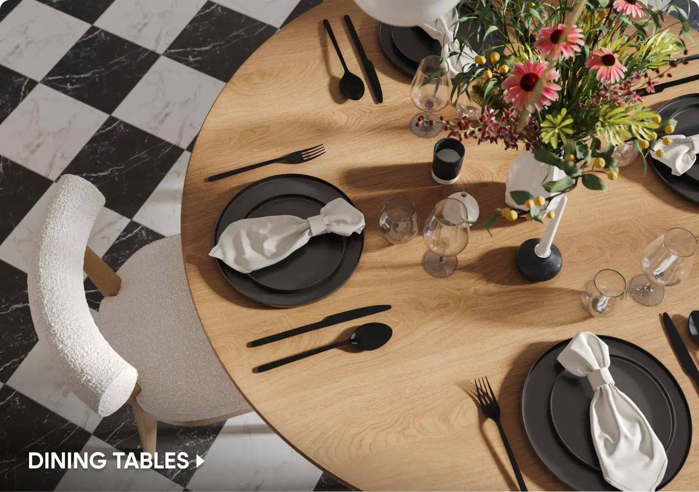 DINING TABLES: A top-down view of a round wooden dining table set with black plates, matte black cutlery, and a floral centerpiece.