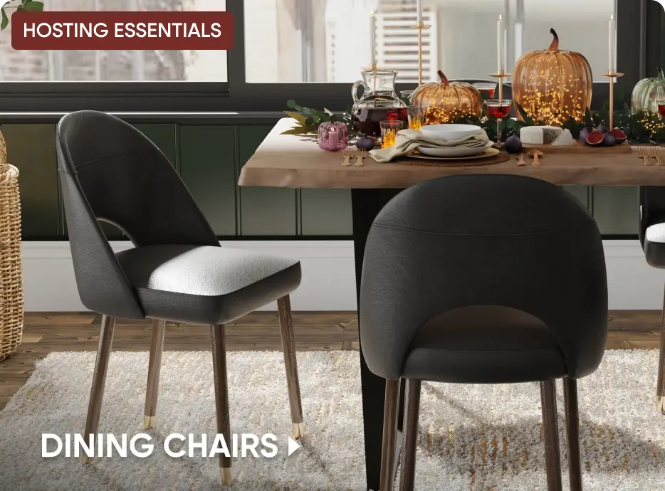 HOSTING ESSENTIALS DINING CHAIRS. Two modern black dining chairs with wooden legs set at a table decorated for autumn.