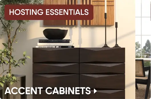 HOSTING ESSENTIALS ACCENT CABINETS. A dark wood, geometric-patterned accent cabinet topped with books and candlesticks.