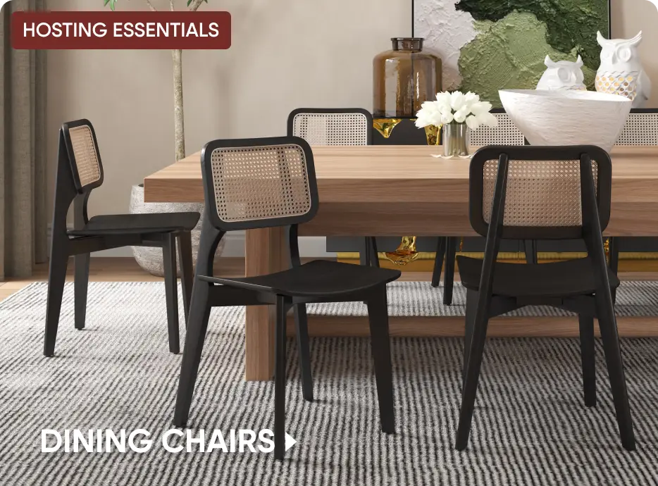 HOSTING ESSENTIALS DINING CHAIRS. Three modern black wooden dining chairs with cane backrests around a wooden table.