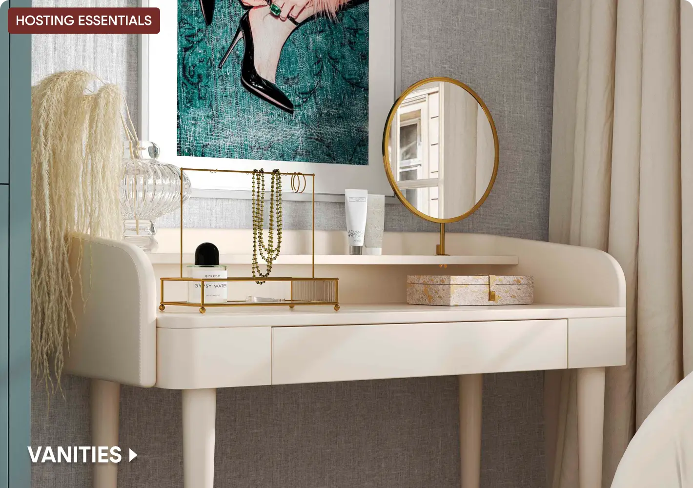 HOSTING ESSENTIALS VANITIES. A modern cream-colored vanity table with a gold jewelry stand, mirror, and perfume bottle.