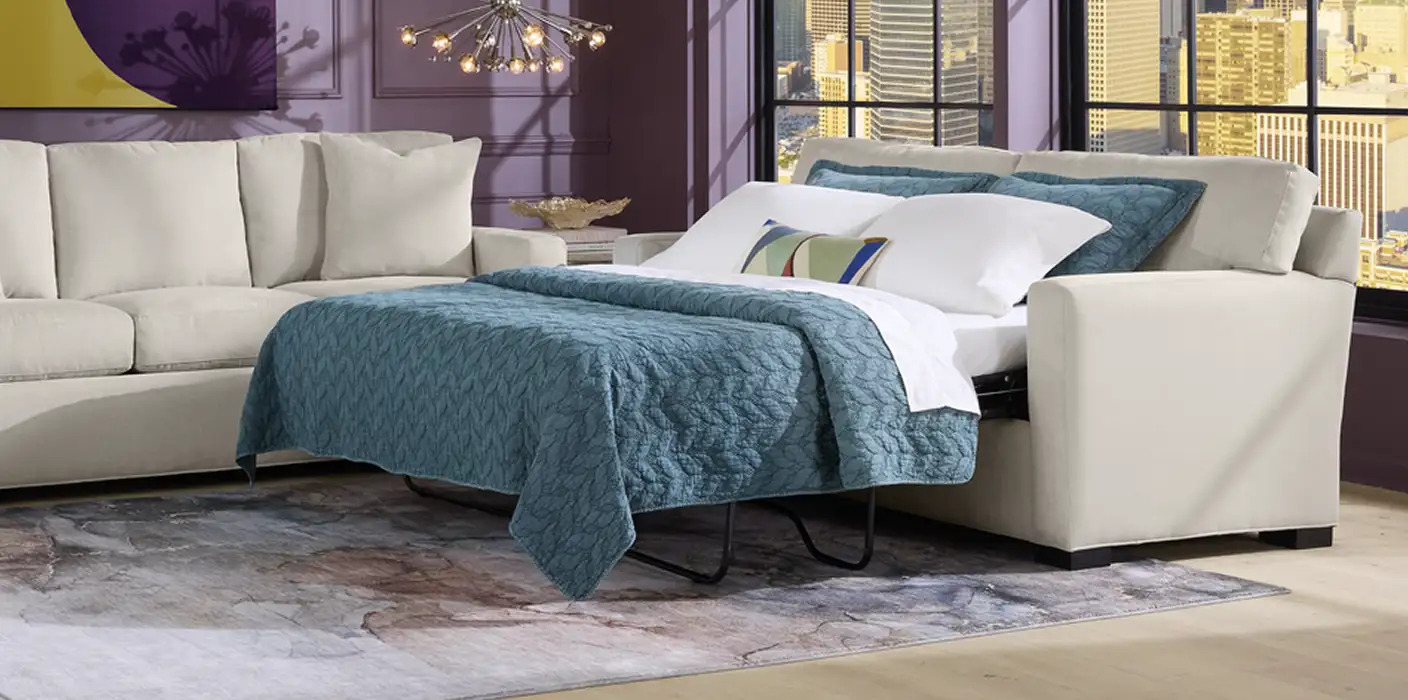 Beige sofa bed with blue bedding.