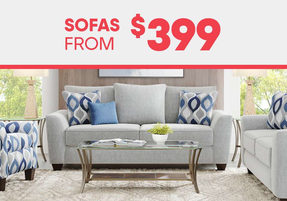 SOFAS FROM $399. A gray sofa with patterned pillows, a glass coffee table, and lamps.
