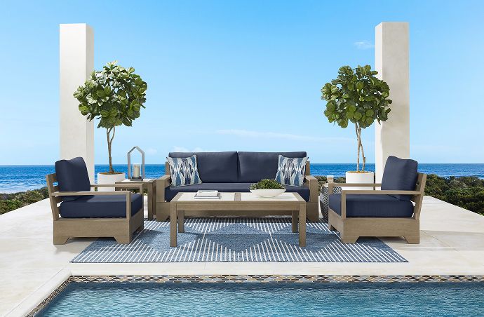 Outdoor furniture set with a sofa, two armchairs, and a coffee table on a patio.

