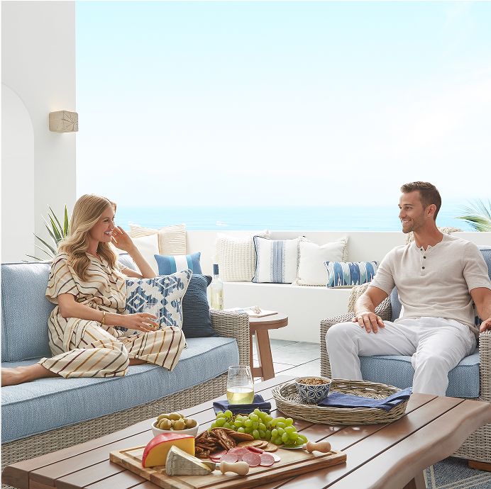 A couple enjoying a charcuterie board on a patio with ocean views.
