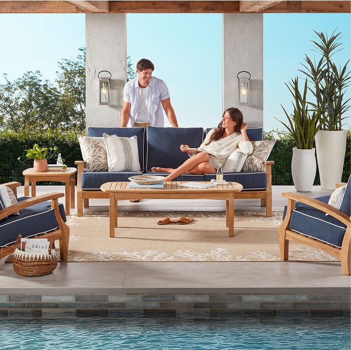 Outdoor furniture set with a couple relaxing by a pool.
