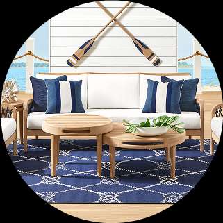 Outdoor furniture set with a sofa, coffee tables, and a blue rug.
