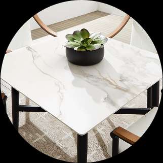 Square marble-top dining table with black legs, a succulent plant, and chairs.
