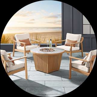 Outdoor seating set with a fire pit table on a patio overlooking the beach.

