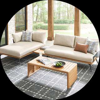Outdoor furniture set with a sofa, chaise lounge, and coffee table on a patterned rug.
