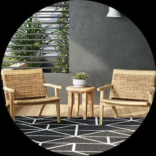Two wooden chairs with woven backs and a small table on a patterned rug.
