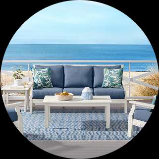Outdoor patio furniture set with blue cushions and ocean view.
