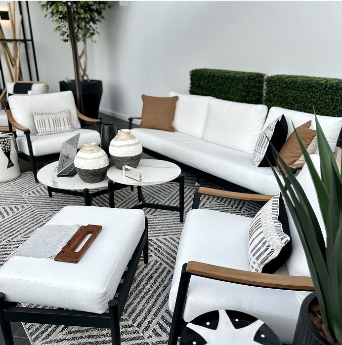 Outdoor furniture set with white cushions, black frames, and wooden armrests.
