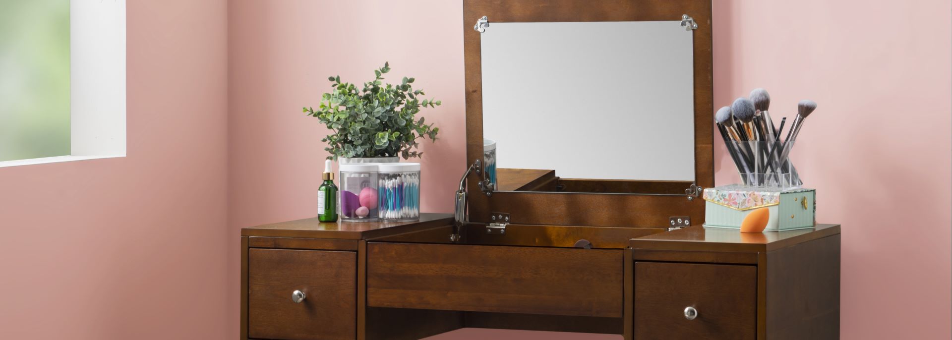 A wooden vanity with a mirror, makeup brushes, and accessories.