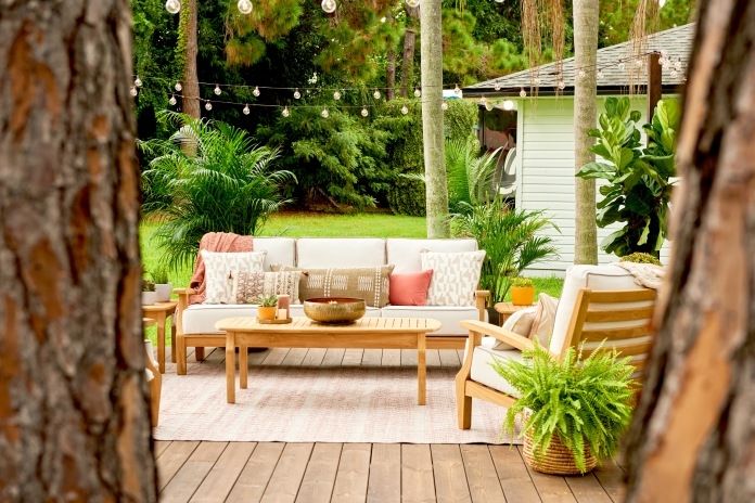Outdoor patio furniture set with a sofa, chairs, and coffee table, surrounded by plants and string lights.
