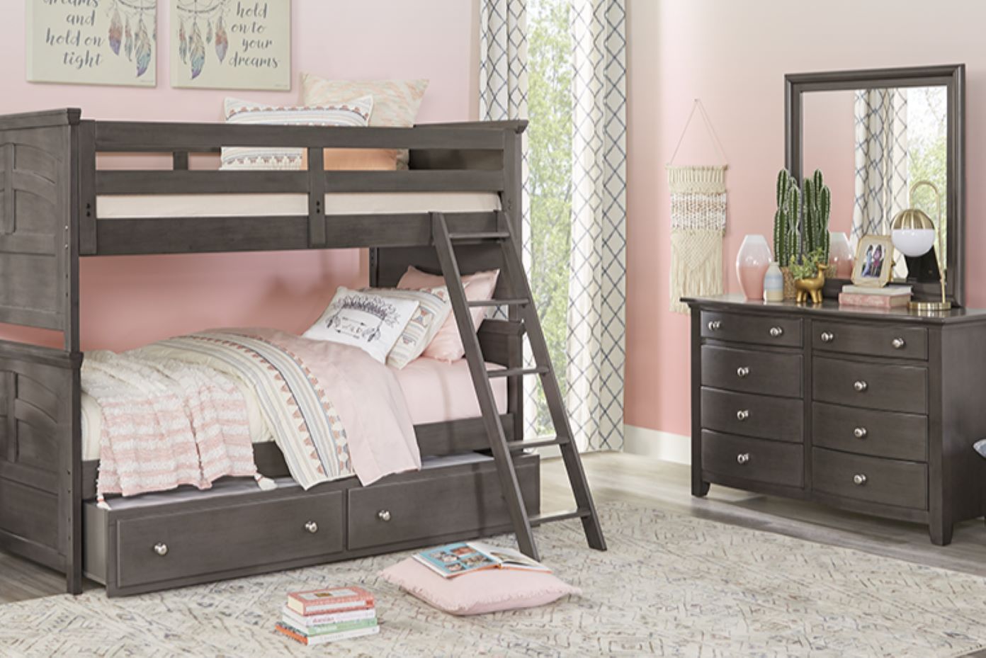 Gray bunk bed with a dresser in a pink room.
