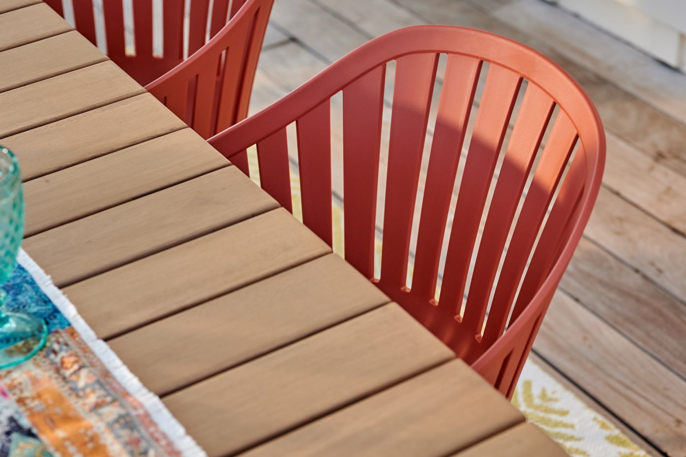 Red outdoor chairs and a wooden table on a deck.
