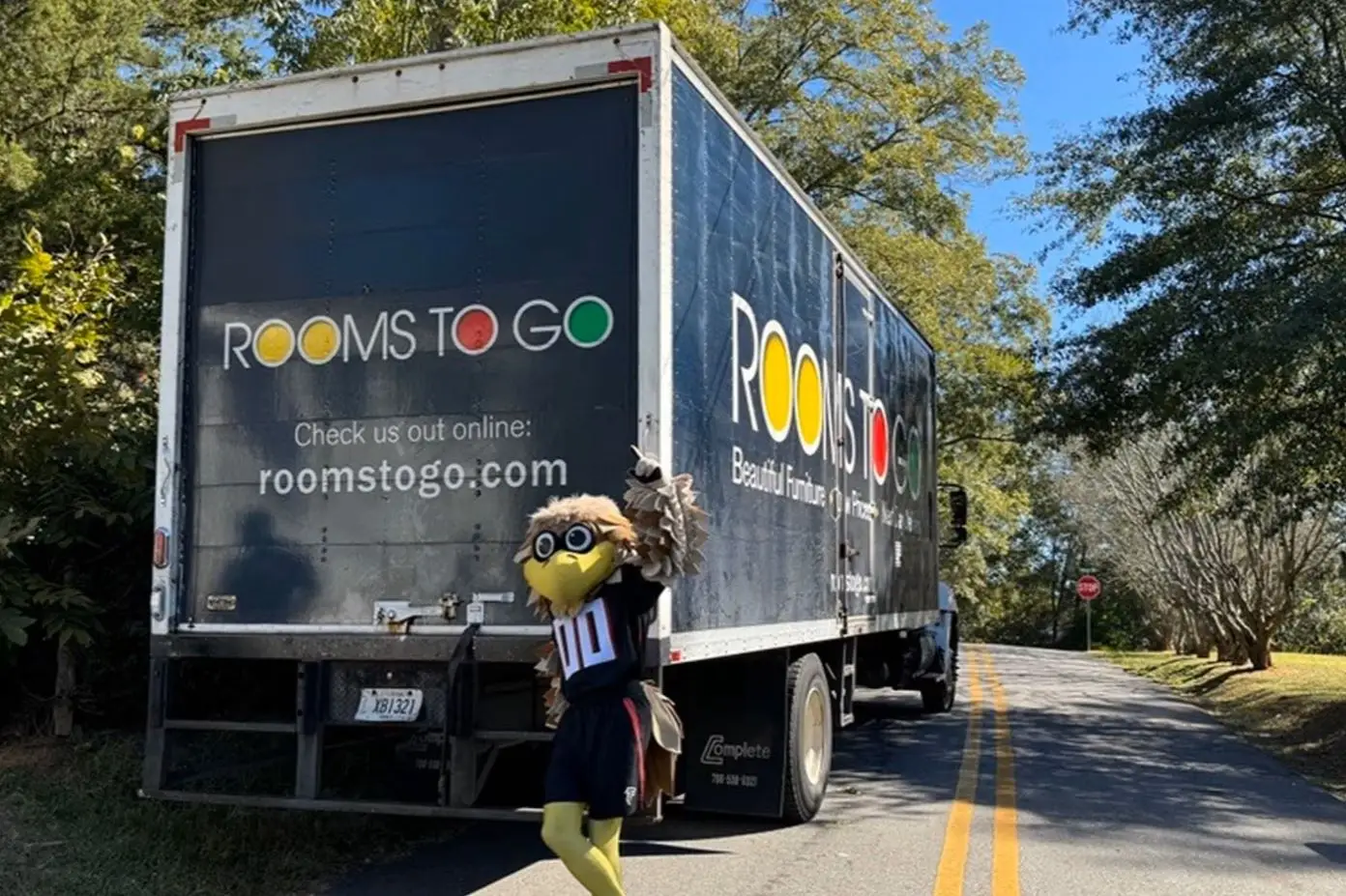 Rooms to Go truck with a mascot in front of it.
