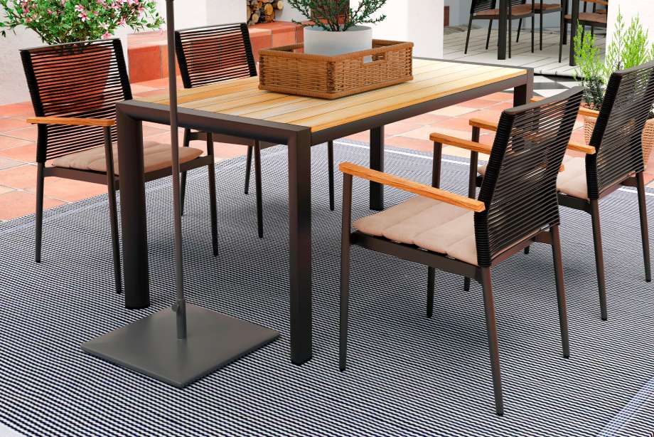 Outdoor dining set with a table, chairs, and a rug.
