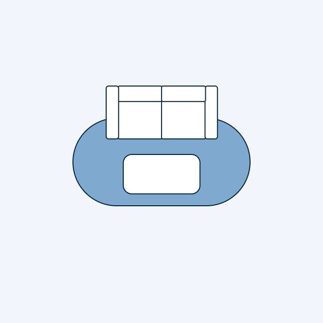 A blue oval rug with a white sofa on top. There is a white rectangle in the middle of the rug.
