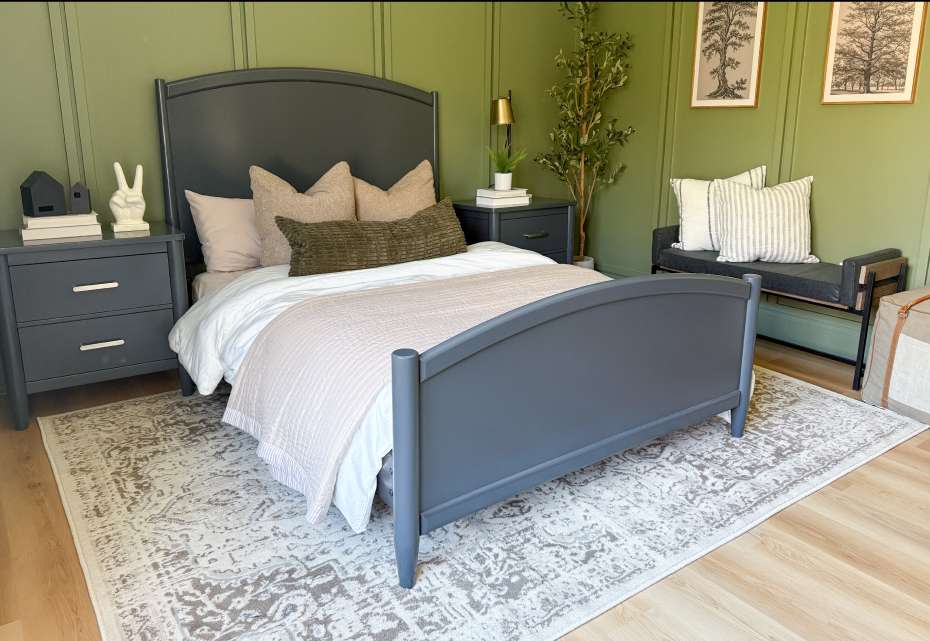 A bedroom with a gray bed, nightstands, and a rug. The walls are green.
