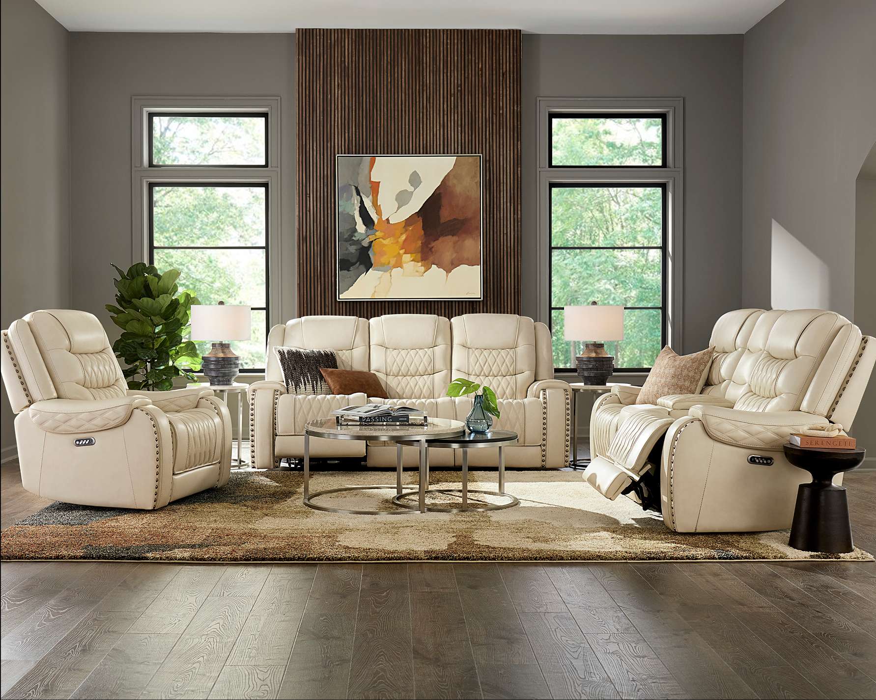 A living room with cream-colored leather furniture, a rug, and a painting.
