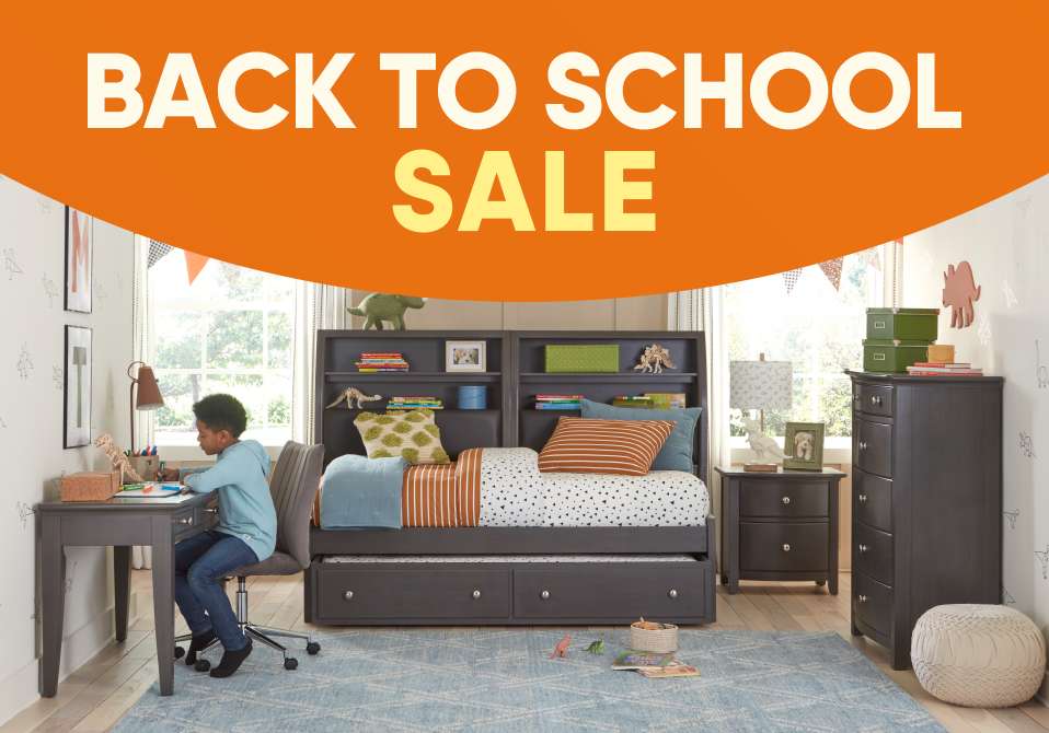 BACK TO SCHOOL SALE. A child's bedroom with a bed, desk, and dresser.

