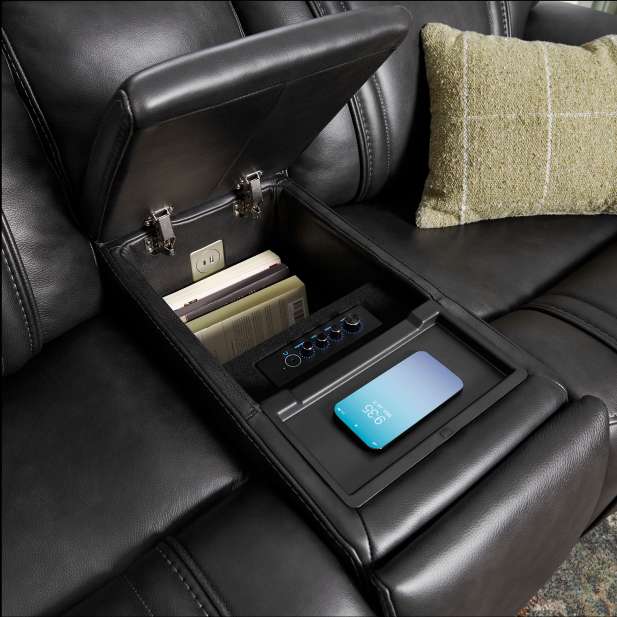 Black leather sofa with an open storage compartment, a phone, and a pillow.
