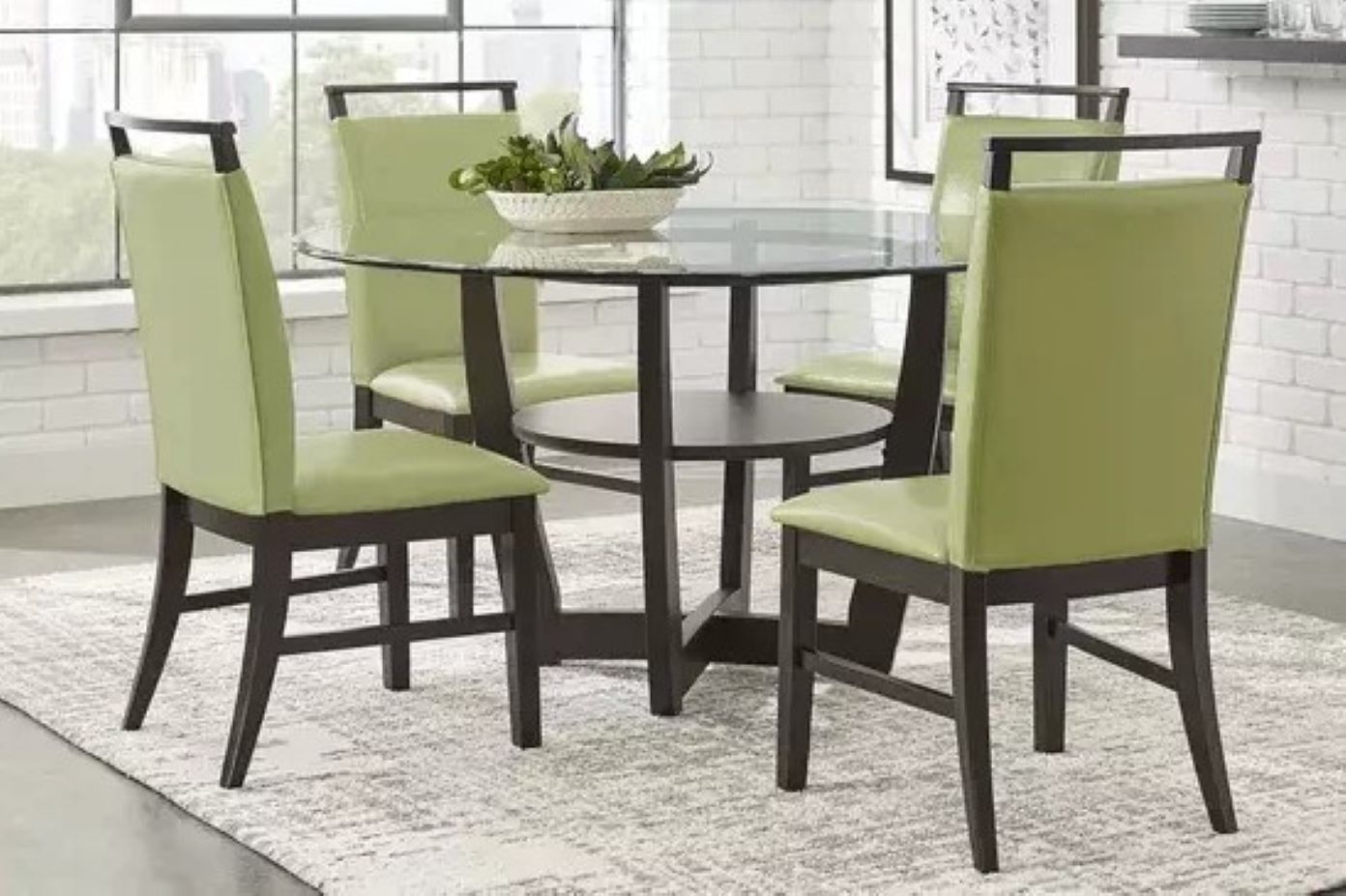 Round glass dining table with four green chairs.
