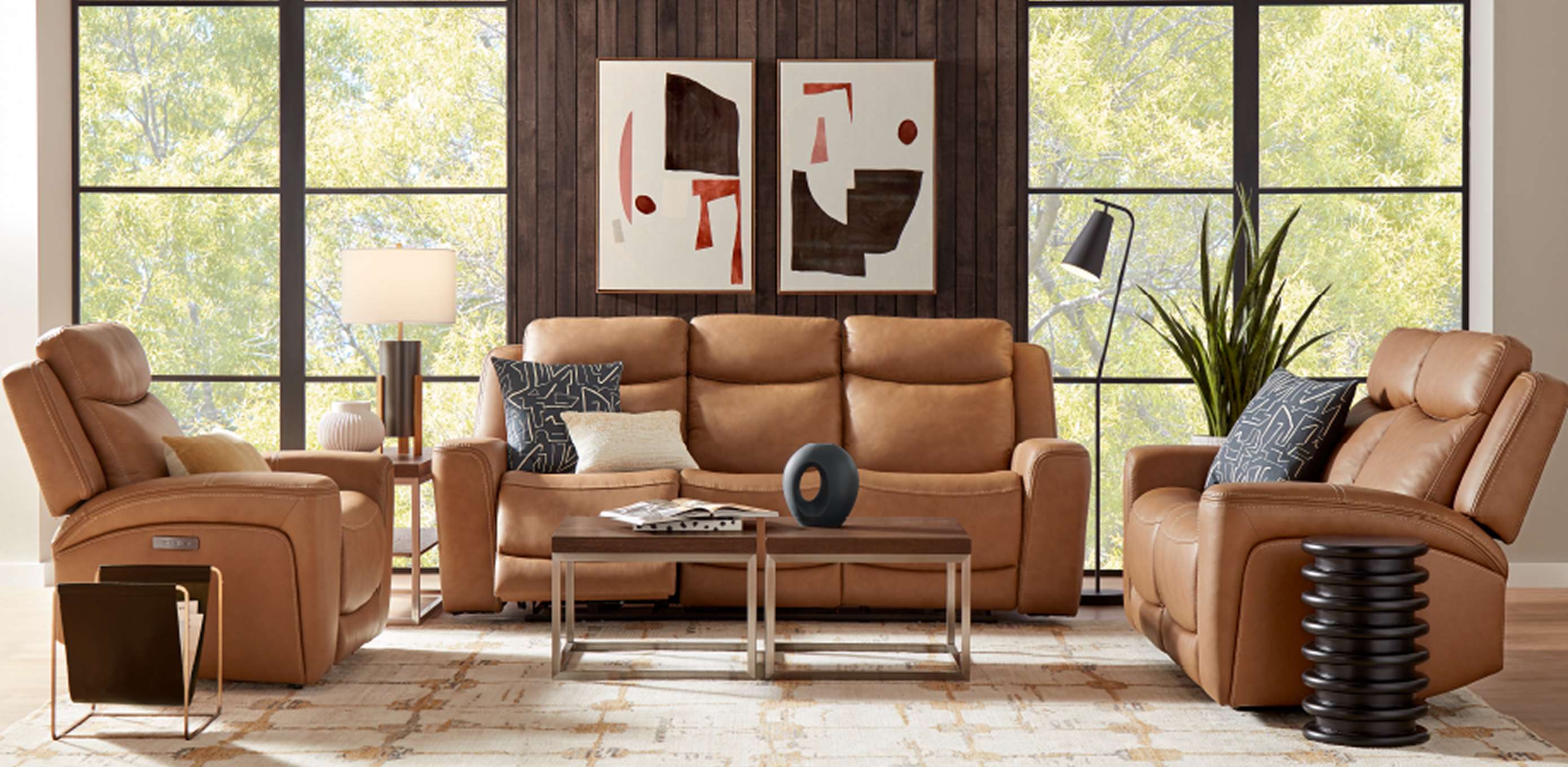 A living room with brown leather furniture, a rug, and artwork.
