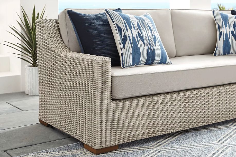 Wicker outdoor sofa with blue patterned pillows.
