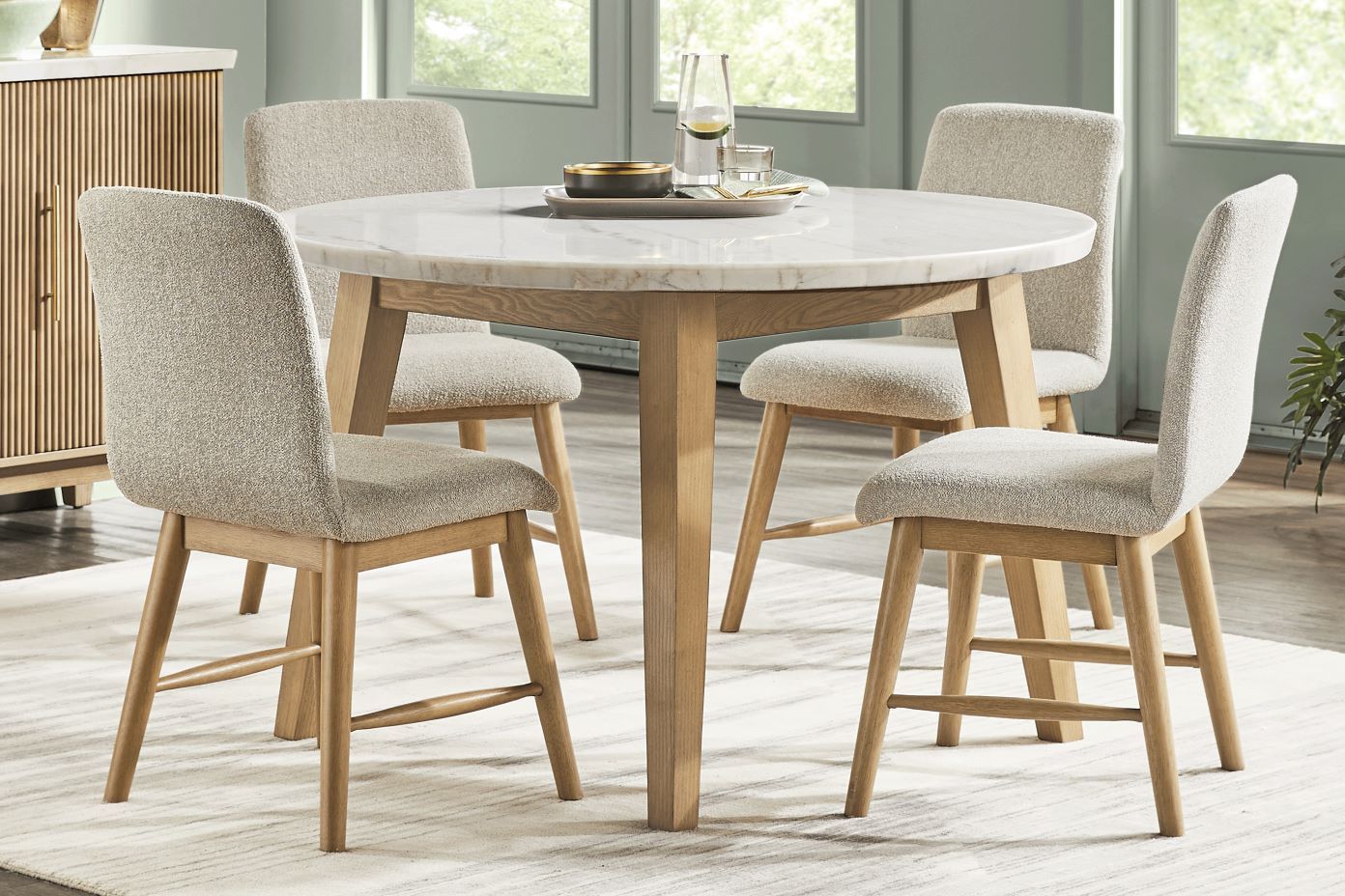 Round dining table with four upholstered chairs.
